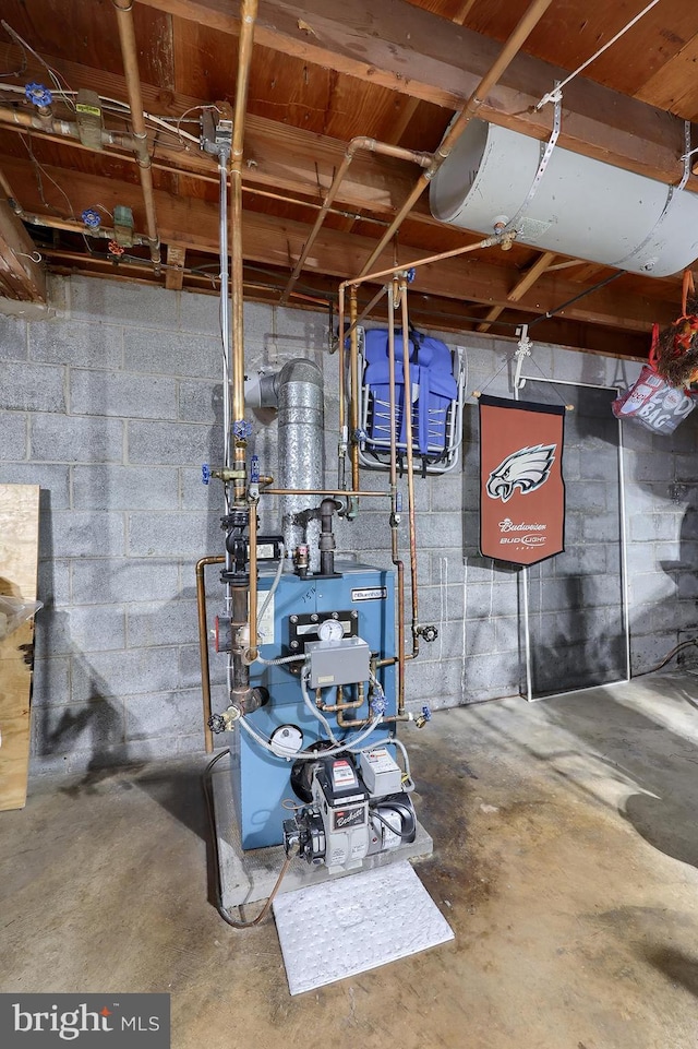unfinished basement featuring a heating unit and concrete block wall