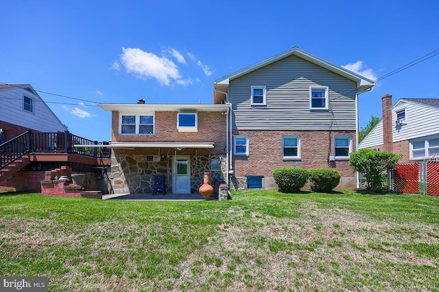 back of property featuring a yard, a wooden deck, and stairway