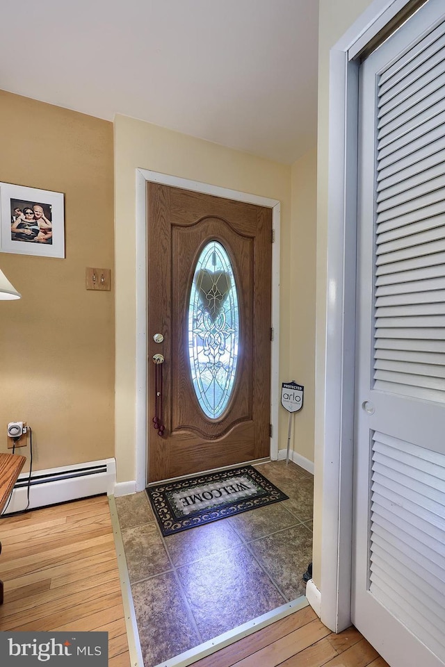 entrance foyer with baseboard heating, wood finished floors, and baseboards