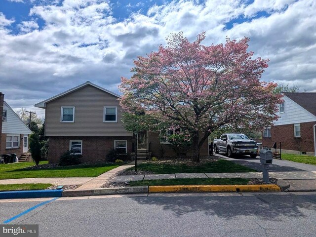 view of front of house featuring brick siding, driveway, and a front lawn