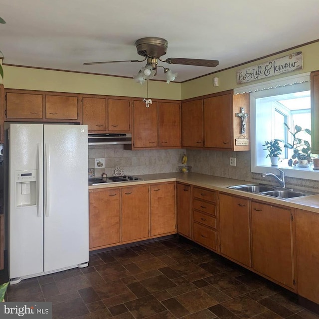 kitchen with white refrigerator with ice dispenser, a sink, light countertops, ceiling fan, and backsplash