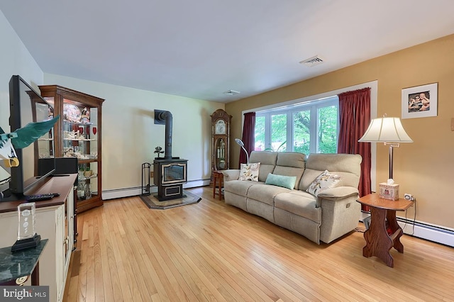living area with a wood stove, a baseboard radiator, and light wood-style floors