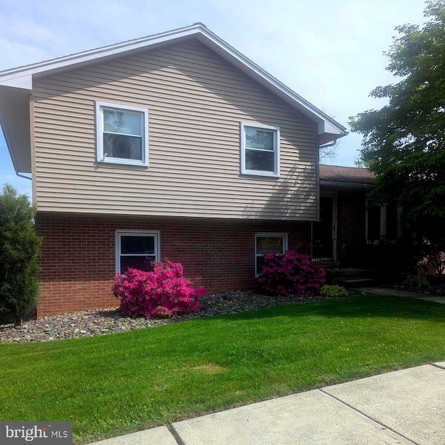view of side of property featuring brick siding and a yard