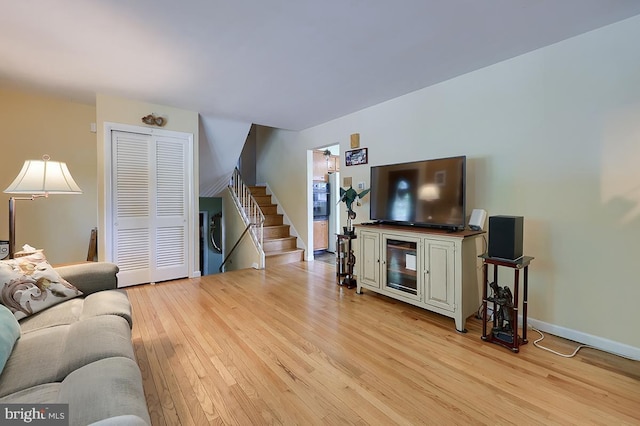 living area with stairs, light wood-style flooring, and baseboards