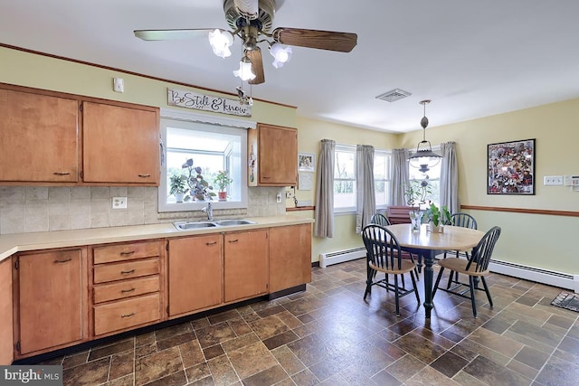 kitchen with a baseboard radiator, a sink, a ceiling fan, stone tile flooring, and decorative backsplash