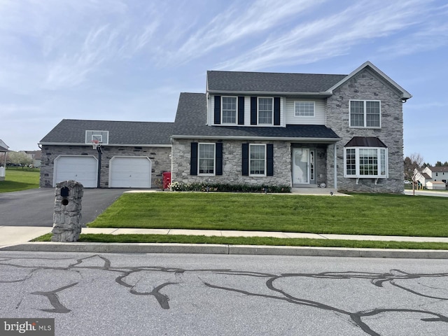 traditional home with stone siding, a shingled roof, a front yard, and driveway