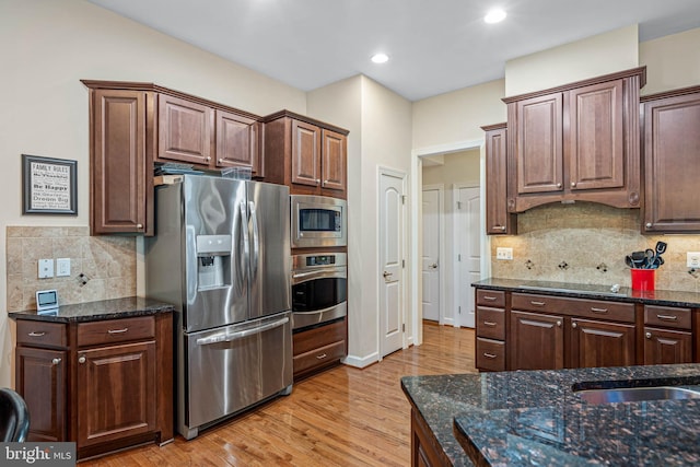 31027 Scissorbill Rd, Ocean View, DE 19970 - kitchen featuring appliances with stainless steel finishes, backsplash, light wood-style floors, dark stone countertops, and recessed lighting