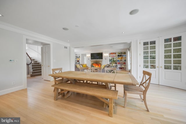 5033 Tilden St NW, Washington, DC 20016 - dining room with crown molding, a lit fireplace, light wood-type flooring, stairs, and baseboards