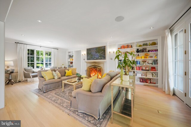 5033 Tilden St NW, Washington, DC 20016 - living room with light wood finished floors, built in shelves, a warm lit fireplace, crown molding, and recessed lighting