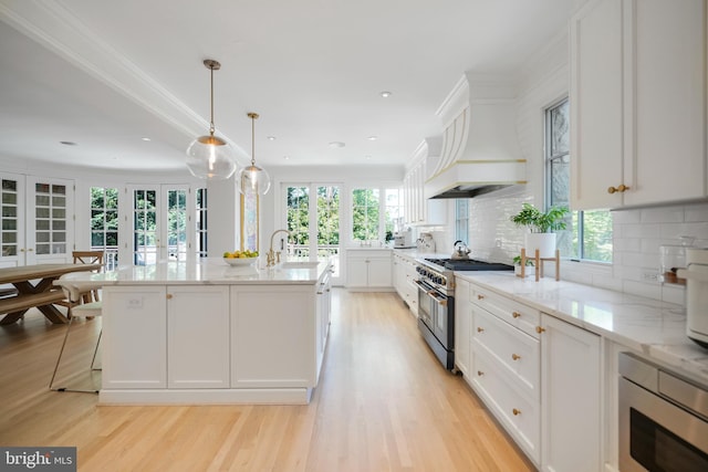 5033 Tilden St NW, Washington, DC 20016 - kitchen featuring high end stove, white cabinetry, built in microwave, tasteful backsplash, and light wood-type flooring