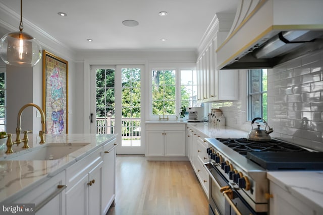 5033 Tilden St NW, Washington, DC 20016 - kitchen featuring stainless steel stove, a sink, ventilation hood, white cabinetry, and healthy amount of natural light