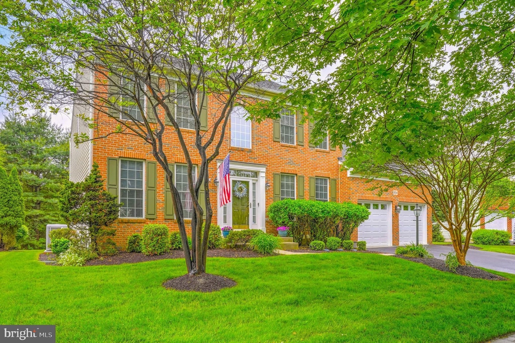 colonial home featuring driveway, a front yard, and brick siding
