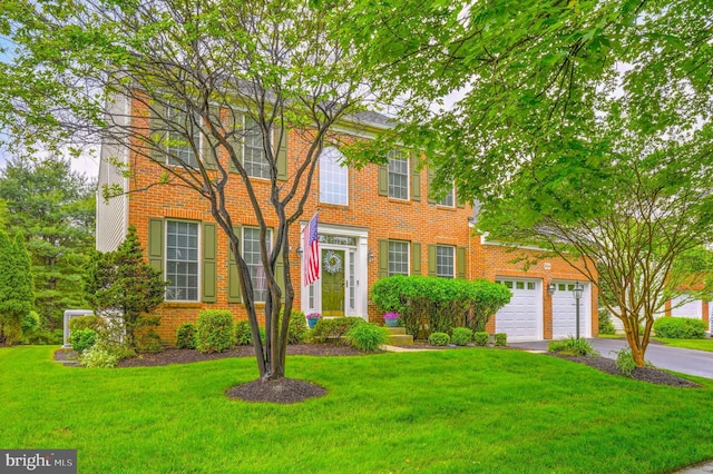 colonial home featuring driveway, a front yard, and brick siding