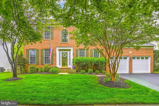 view of front of house with driveway, a garage, a front yard, brick siding, and central air condition unit