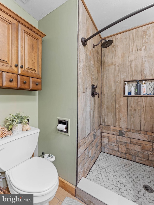 bathroom with a shower stall, toilet, and baseboards
