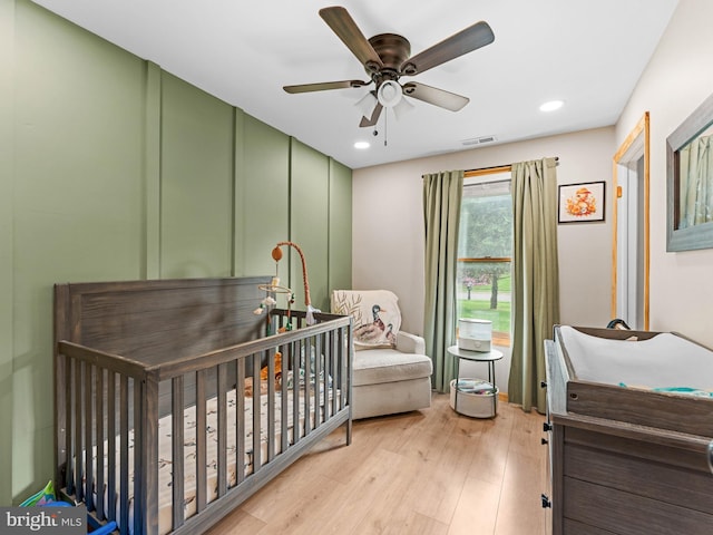 bedroom with light wood finished floors, recessed lighting, ceiling fan, and a crib
