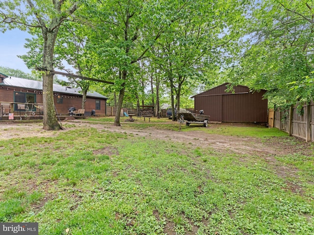 view of yard featuring fence, a pole building, and an outdoor structure