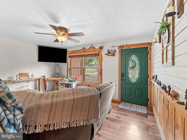 living room with a textured ceiling, ceiling fan, and wood finished floors