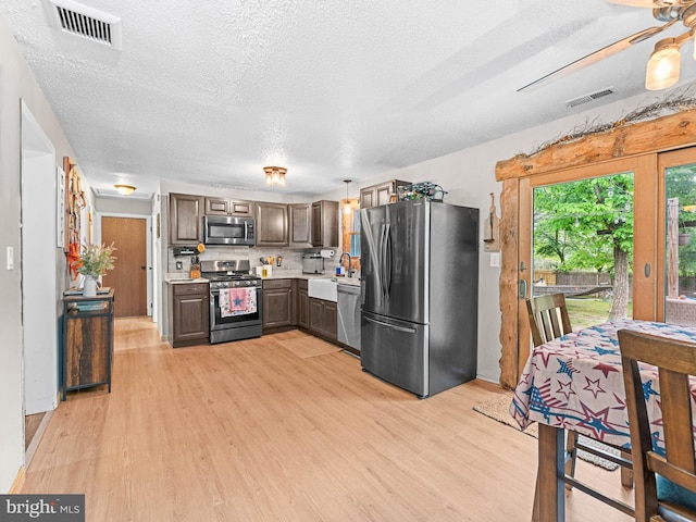 kitchen with stainless steel appliances, light countertops, light wood-style flooring, dark brown cabinets, and a textured ceiling