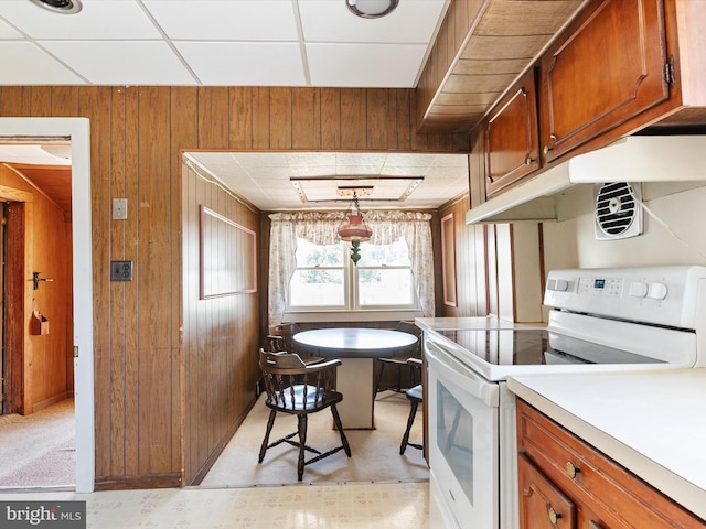 108 S 2nd St, Denton, MD 21629 - kitchen featuring white electric range oven, wooden walls, brown cabinets, a drop ceiling, and under cabinet range hood