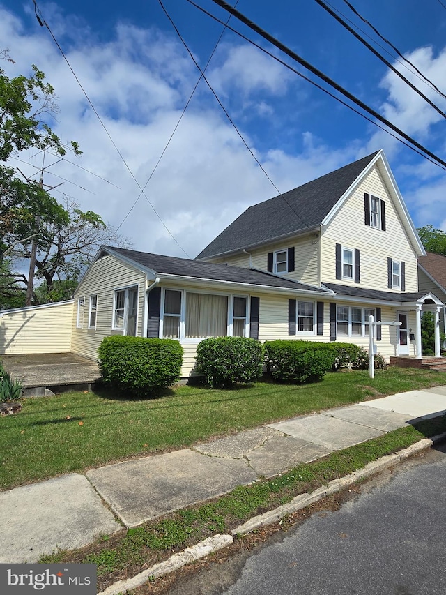traditional-style home featuring a front yard and roof with shingles