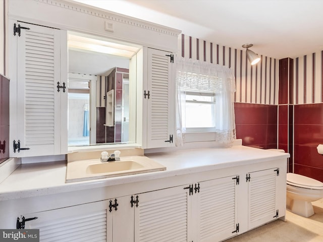 108 S 2nd St, Denton, MD 21629 - bathroom with toilet, tile walls, vanity, and wallpapered walls