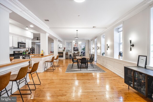 237 N Bread St Unit 2, Philadelphia, PA 19106 - dining space featuring a decorative wall, ornamental molding, light wood finished floors, and wainscoting
