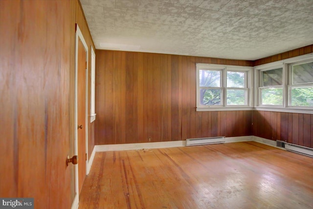 129 Shippensburg Rd, Shippensburg, PA 17257 - spare room with a baseboard radiator, wood finished floors, baseboards, wood walls, and a baseboard heating unit