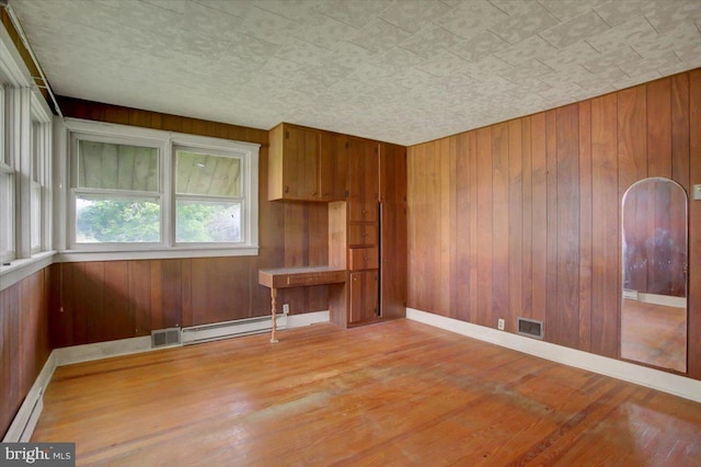 129 Shippensburg Rd, Shippensburg, PA 17257 - unfurnished room featuring a baseboard radiator, wood finished floors, wooden walls, and baseboards