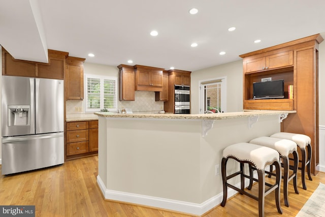 1802 24th St S, Arlington, VA 22202 - kitchen featuring appliances with stainless steel finishes, decorative backsplash, brown cabinets, a kitchen breakfast bar, and recessed lighting