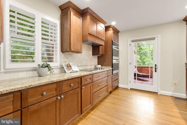 1802 24th St S, Arlington, VA 22202 - kitchen with light wood-type flooring, decorative backsplash, double oven, black electric cooktop, and brown cabinets