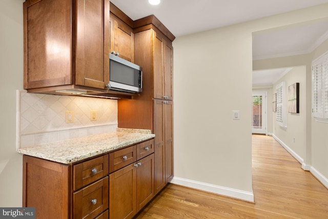 1802 24th St S, Arlington, VA 22202 - kitchen with backsplash, light wood-style floors, light stone countertops, brown cabinetry, and crown molding