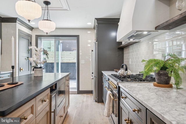 826 Tasker St, Philadelphia, PA 19148 - kitchen with custom range hood, high end stainless steel range oven, light wood-style floors, pendant lighting, and backsplash