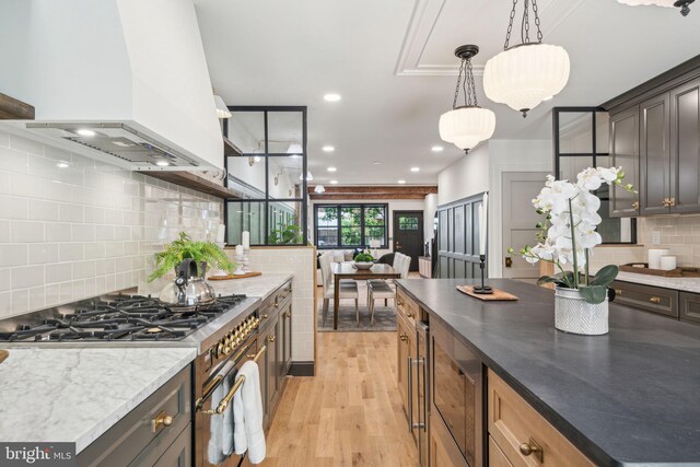 826 Tasker St, Philadelphia, PA 19148 - kitchen featuring stainless steel appliances, custom range hood, light wood-style flooring, tasteful backsplash, and decorative light fixtures
