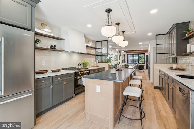 826 Tasker St, Philadelphia, PA 19148 - kitchen featuring open shelves, stainless steel appliances, a center island, tasteful backsplash, and light wood-style floors