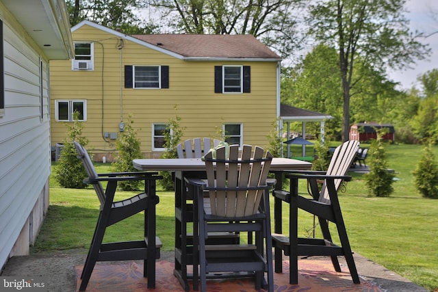 back of house featuring a lawn and roof with shingles