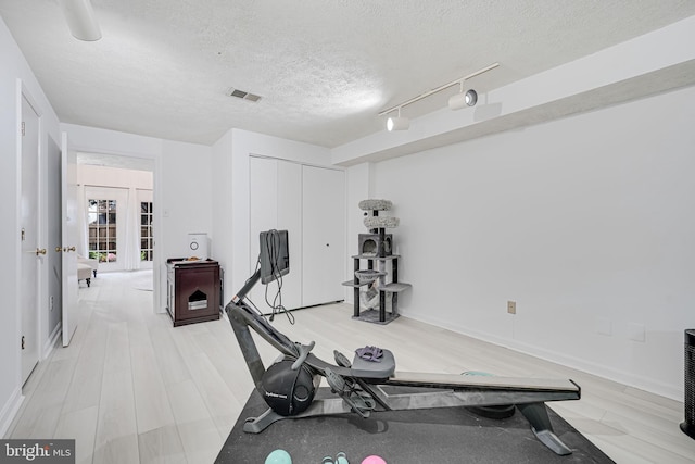 13916 Preacher Chapman Pl, Centreville, VA 20121 - exercise room featuring a textured ceiling, light wood-type flooring, track lighting, and baseboards