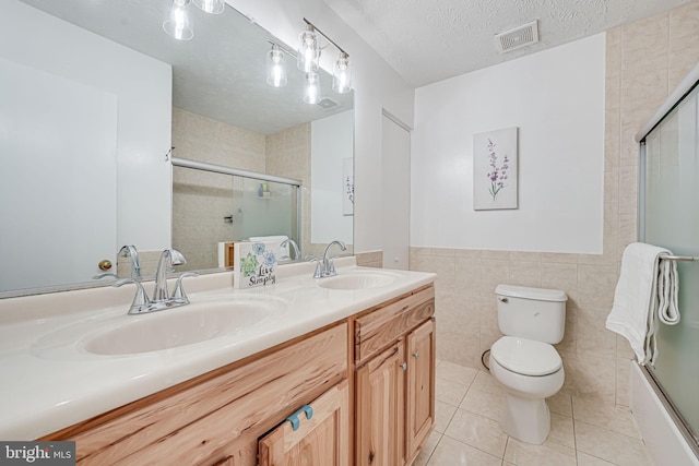 13916 Preacher Chapman Pl, Centreville, VA 20121 - bathroom with double vanity, tile walls, toilet, tile patterned floors, and a textured ceiling