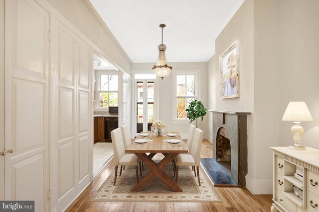 812 E St SE, Washington, DC 20003 - dining area with light wood finished floors, a chandelier, baseboards, a fireplace with raised hearth, and crown molding