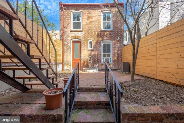 812 E St SE, Washington, DC 20003 - view of front of property featuring stairway, brick siding, a fenced backyard, and central AC unit