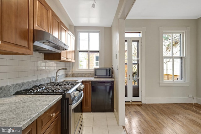 812 E St SE, Washington, DC 20003 - kitchen with appliances with stainless steel finishes, under cabinet range hood, brown cabinetry, and plenty of natural light