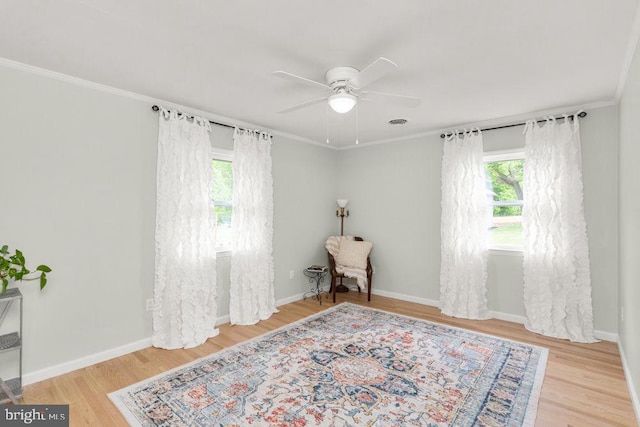 living area featuring ceiling fan, wood finished floors, crown molding, and baseboards