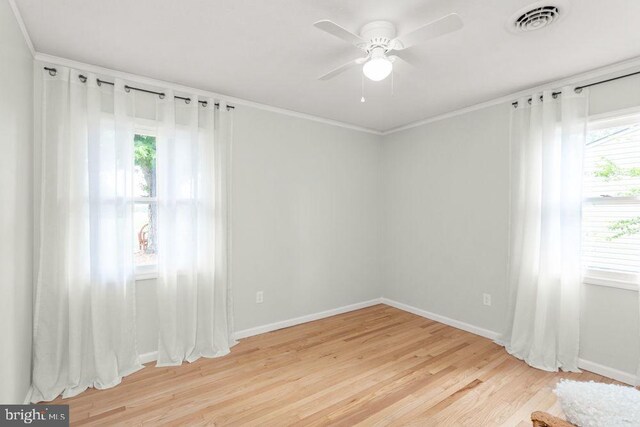 empty room with light wood finished floors, baseboards, ceiling fan, and ornamental molding