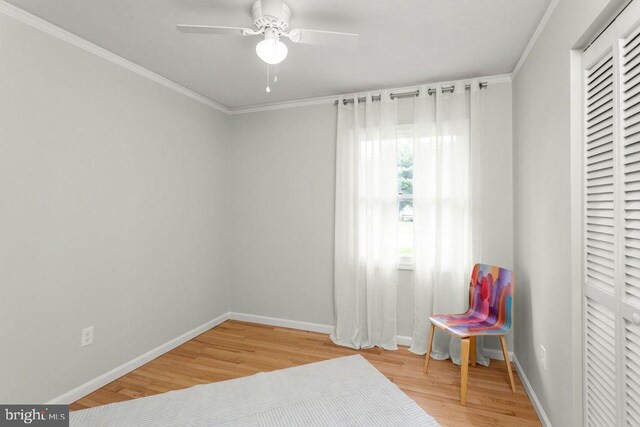 living area with wood finished floors, ornamental molding, baseboards, and a ceiling fan