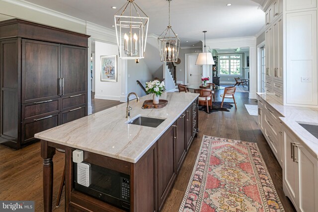 280 Carter Rd, Princeton, NJ 08540 - kitchen with a sink, ornamental molding, dark wood-type flooring, white cabinets, and a kitchen island with sink