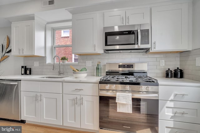 1636 40th St SE, Washington, DC 20020 - kitchen featuring appliances with stainless steel finishes, a sink, white cabinetry, and decorative backsplash