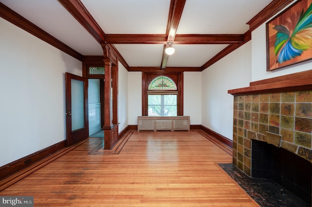 unfurnished living room featuring light wood-style flooring, a fireplace with flush hearth, decorative columns, radiator, and baseboards