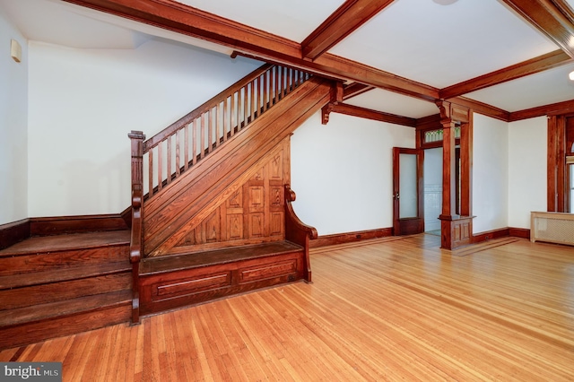 stairs featuring wood finished floors, decorative columns, beamed ceiling, and baseboards