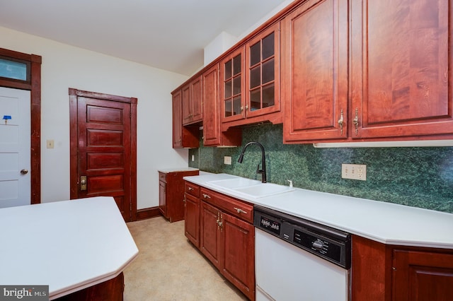 kitchen with white dishwasher, a sink, backsplash, light countertops, and glass insert cabinets