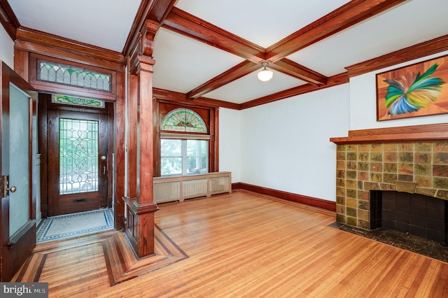 entrance foyer featuring light wood-type flooring, coffered ceiling, a fireplace, beam ceiling, and baseboards